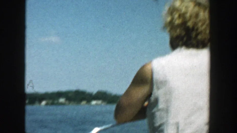 1957 Wisconsin home-movie frame showing a woman from behind beside a partial man as the boat faces open water.