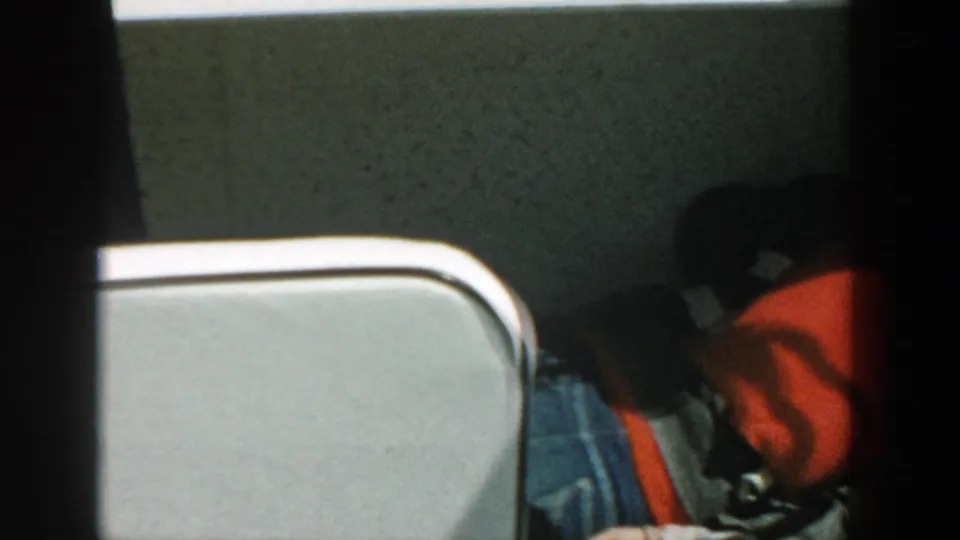 1957 Wisconsin 8mm frame from a boat interior or deck opening, with a person partly hidden beside a red life jacket and white boat edge.