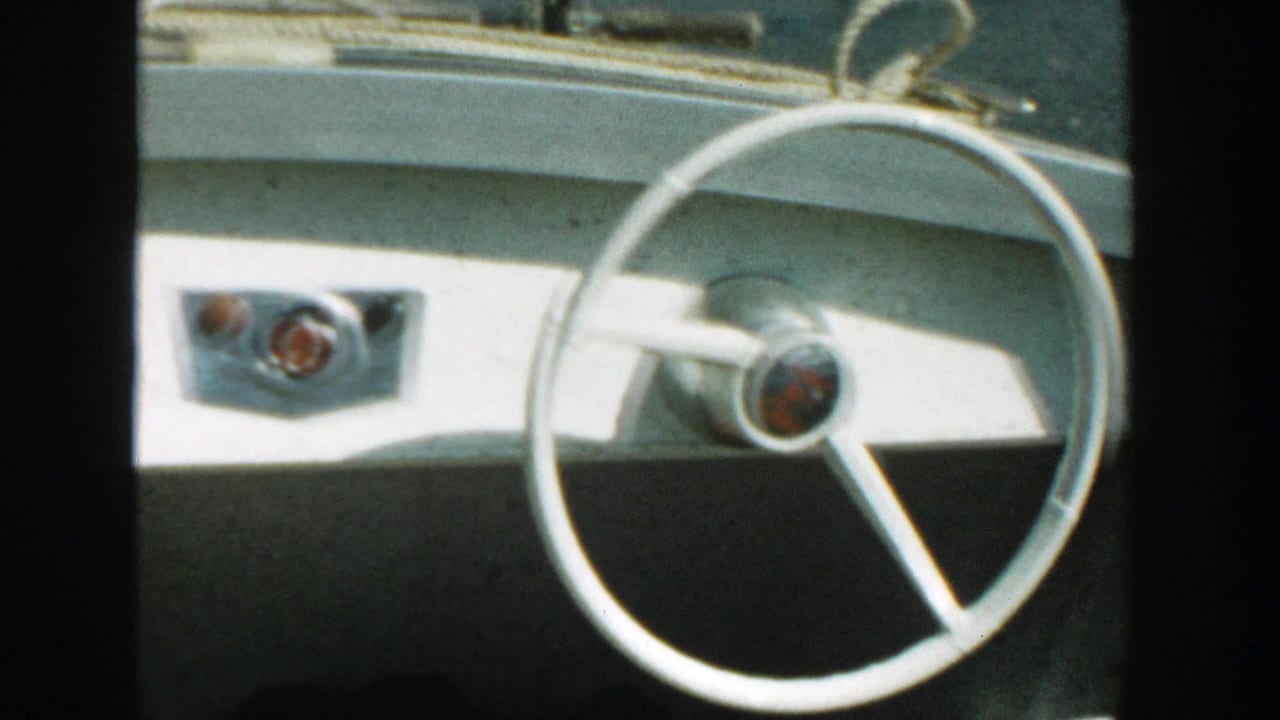 White boat dashboard with a round steering wheel and control knobs.