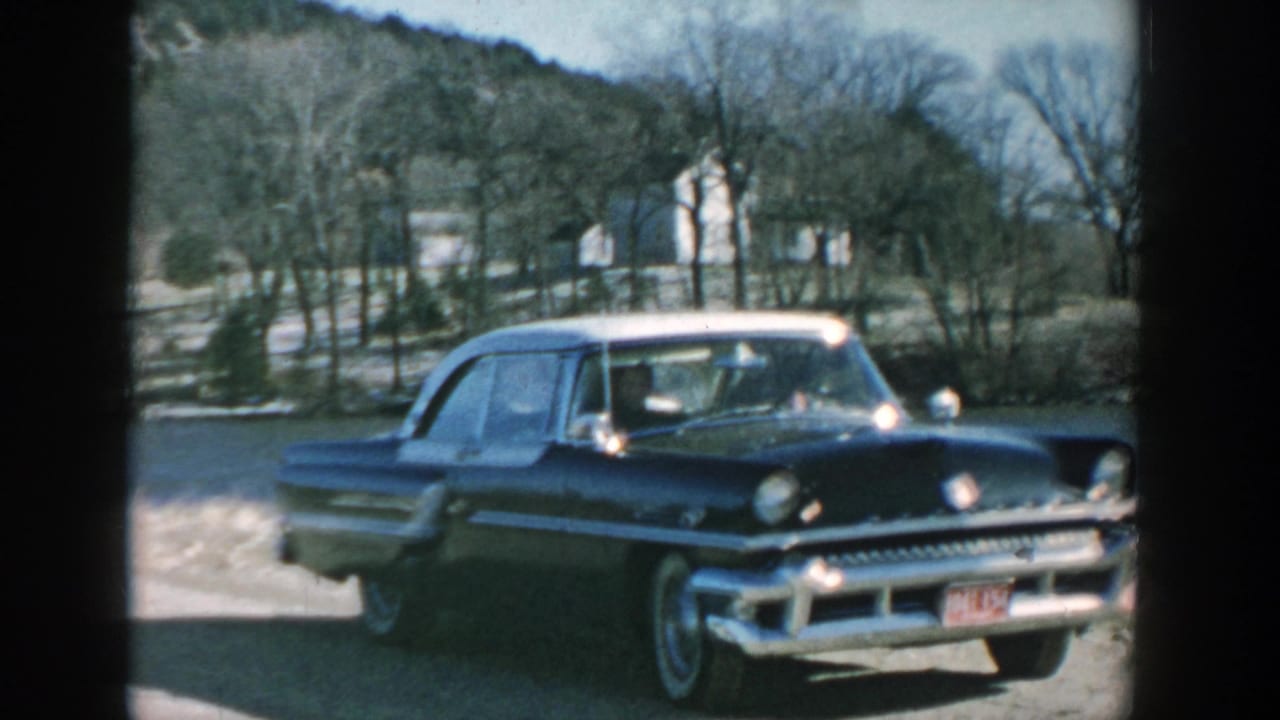 Black and white-roof sedan seen from the front beside a rural road or gravel area.