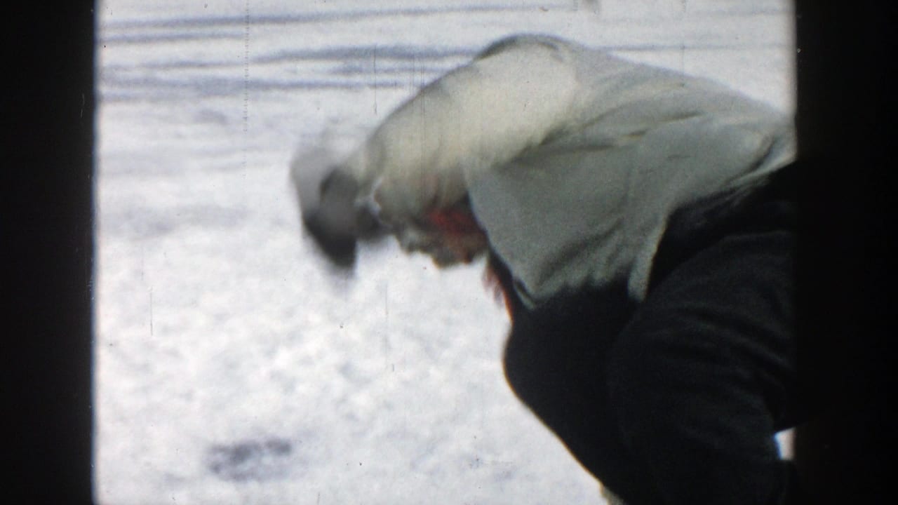 In 1957 Wisconsin home-movie footage, a woman in a white coat bends low on the snow-covered ice of a frozen lake.