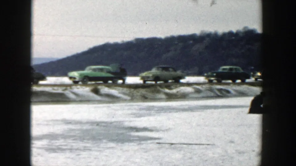 The closing frame shows a green sedan and other cars on a snowy Wisconsin road, with a wooded hill rising in the background.