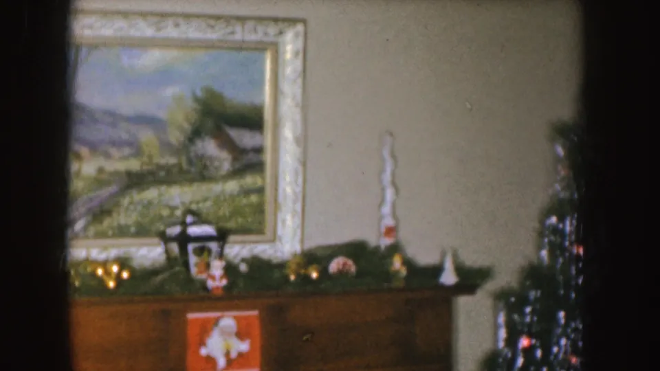 1955 Nebraska home interior showing a landscape painting, garlanded mantel, small decorations, and the edge of a Christmas tree.
