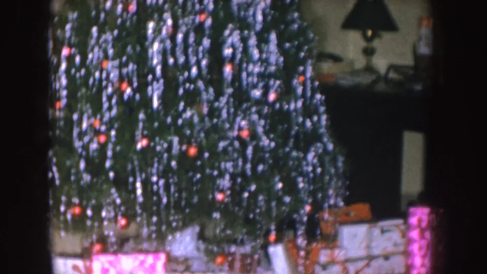 Nebraska 1955 frame with a silver-tinsel Christmas tree, red ornaments or lights, and wrapped gifts below.
