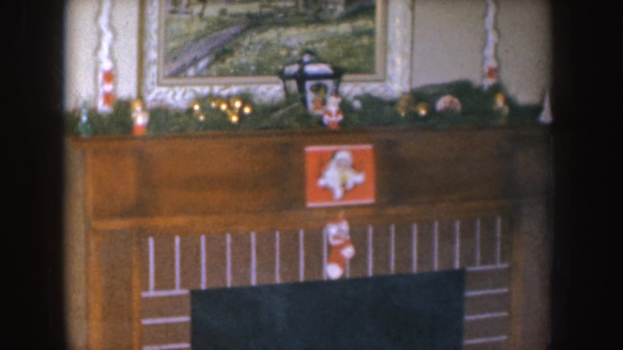 Christmas mantel with stocking, garland, candles, and framed wall art.