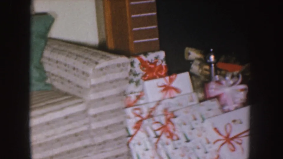 Wrapped Christmas presents with ribbons sit in the same home interior, suggesting a holiday family gathering.