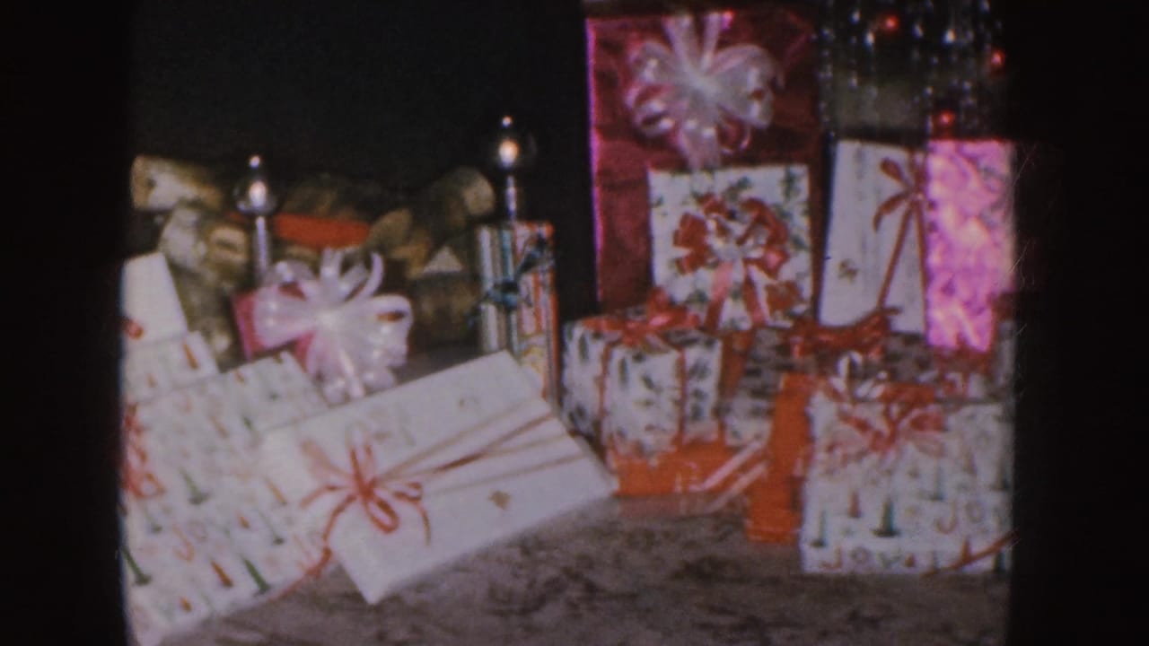 Wrapped Christmas presents with bows arranged near a tree edge.