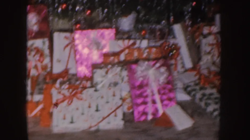 Nebraska 1955 8mm frame showing close-up wrapped holiday gifts with red ribbons and tinsel.