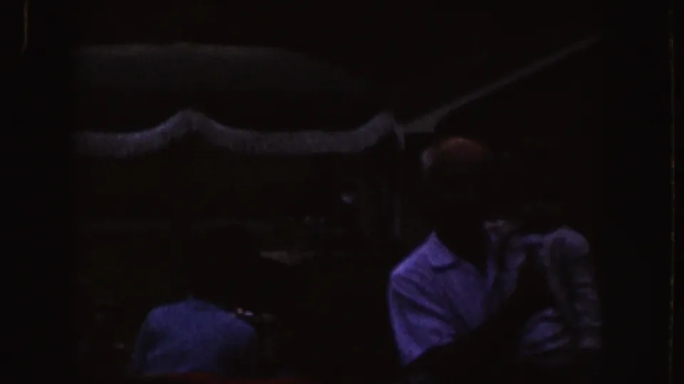 Nebraska 1955 home-movie frame showing adults seated in darkness during what appears to be a film viewing.