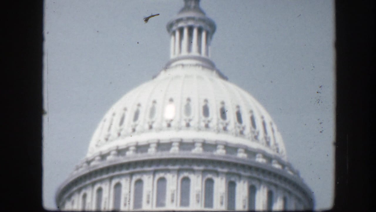 Soft 8mm view of the upper U.S. Capitol dome against a bright sky.