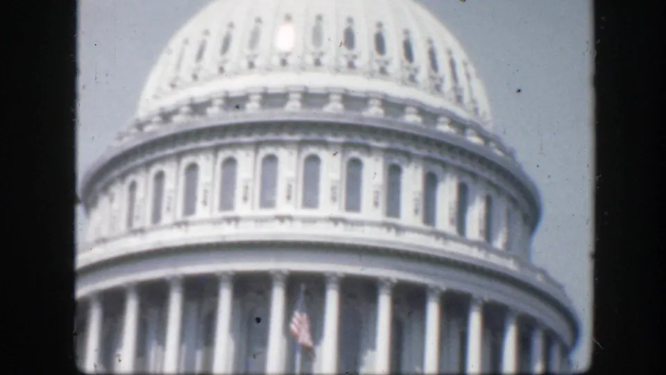 1945 Washington, D.C. frame of the U.S. Capitol dome and rotunda colonnade with a small U.S. flag visible below.