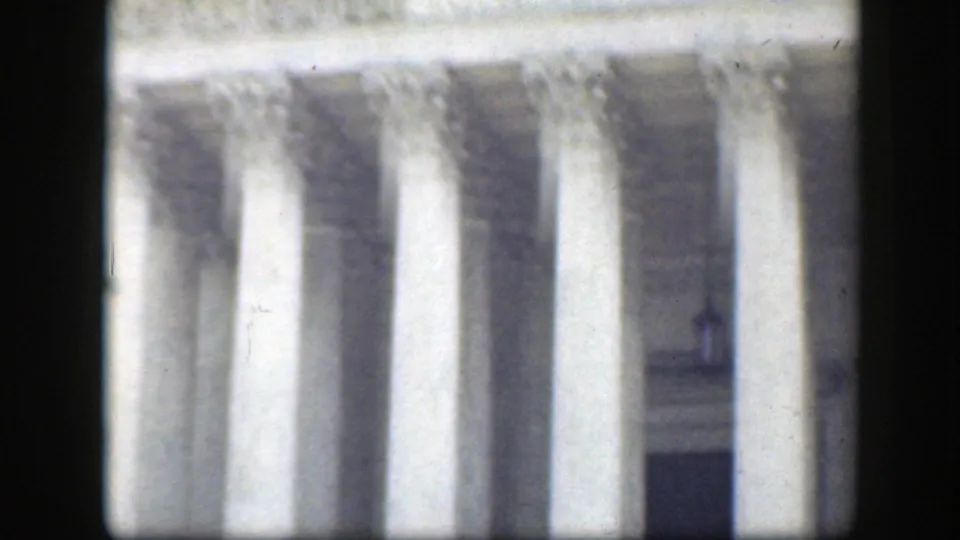 Soft 8mm view of a Washington DC neoclassical facade with large columns and shadowed entrance areas, consistent with the stated 1945 footage.