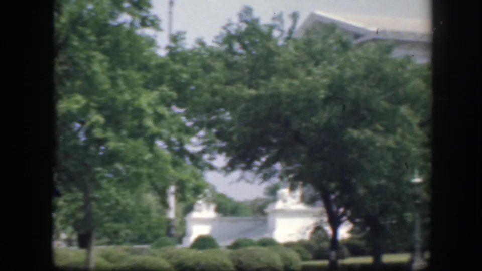 1945 Washington DC frame showing leafy grounds, clipped hedges and a partly hidden white civic building in soft color 8mm.