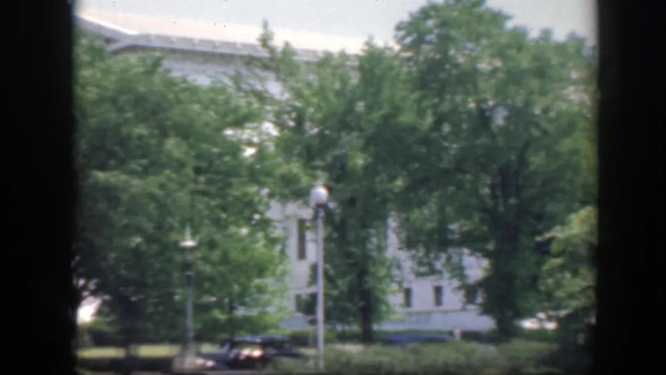 1945 Washington DC home-movie view of a large white building behind leafy trees, with dark borders framing the scene.