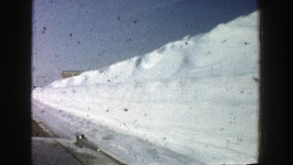 Metadata-supported 1961 Aspen highway view with a snow-covered roadside bank, pale sky, and visible 8mm scan texture.