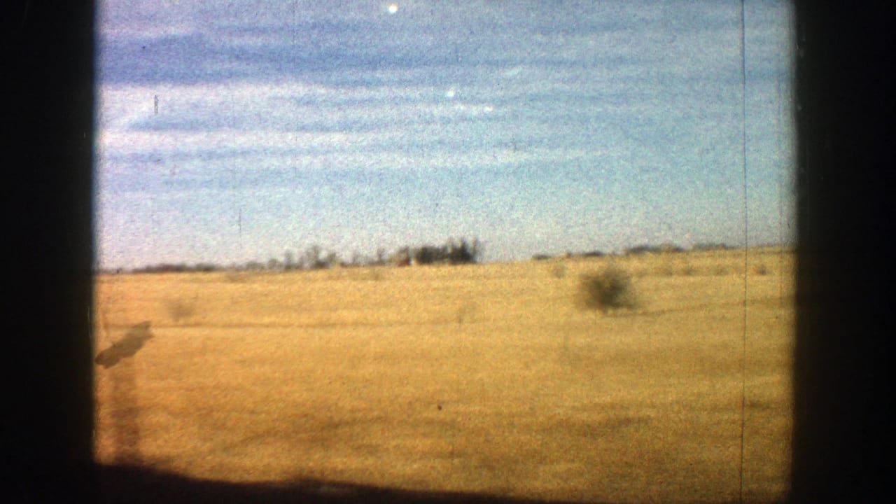 Open brown field under blue sky with dark 8mm frame edges.