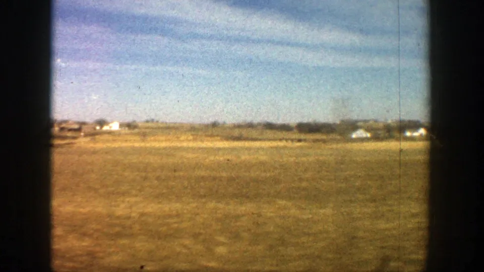1961 8mm landscape near Aspen, Colorado, with scattered distant buildings across a dry open plain.