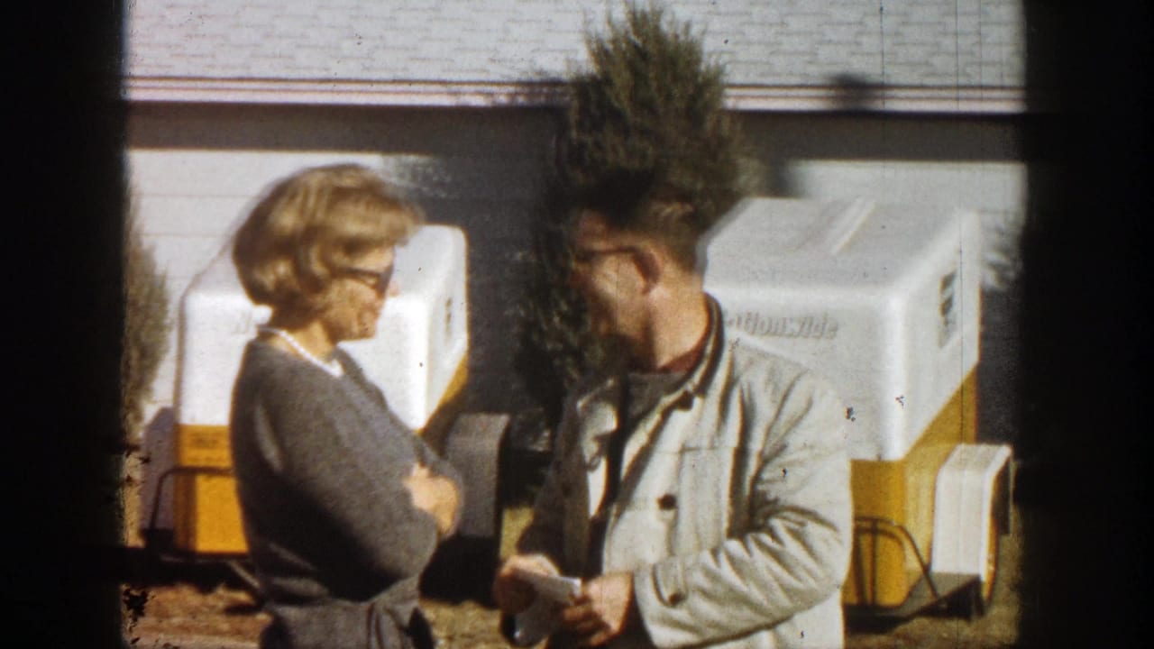 Woman and man standing beside portable coolers outside a house.