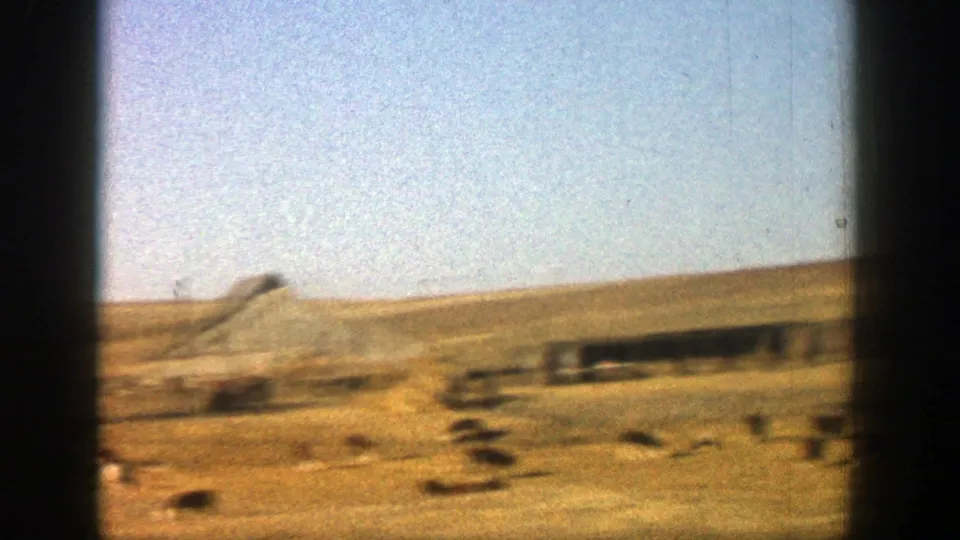 A blurred dry landscape appears from a moving viewpoint, suggesting a travel shot following the couple scene.