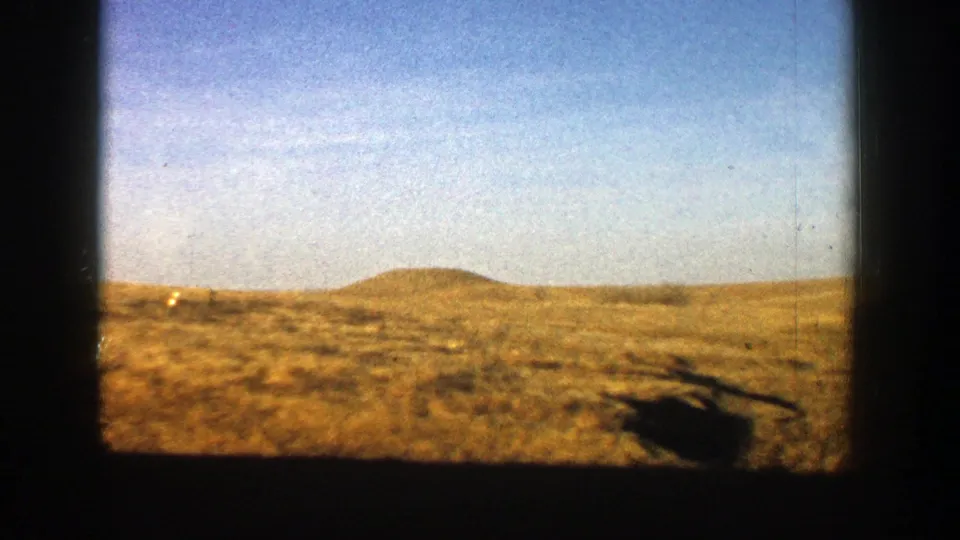 1961 Aspen, Colorado 8mm view of a low rounded hill, dry brushland, pale blue sky, and dark film-edge framing.