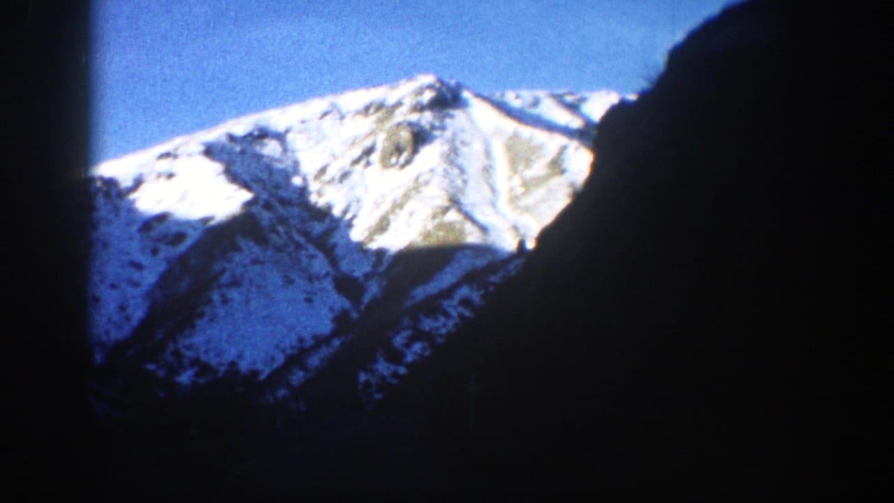 Snowy mountain peak framed by dark film edges and shadowed slopes.