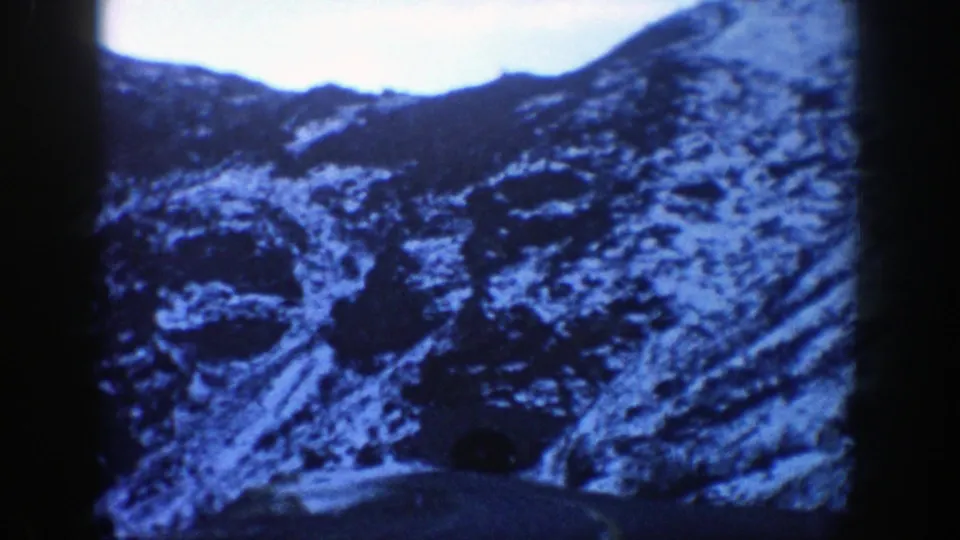 1961 Aspen, Colorado road footage moves closer to a tunnel opening set in snow-dusted mountain rock.
