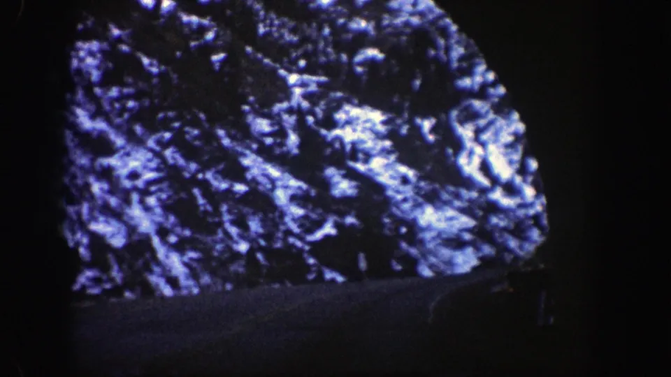 A dark tunnel frame surrounds a bright, irregular view of snow-covered rocky terrain in 1961 Aspen, Colorado footage.