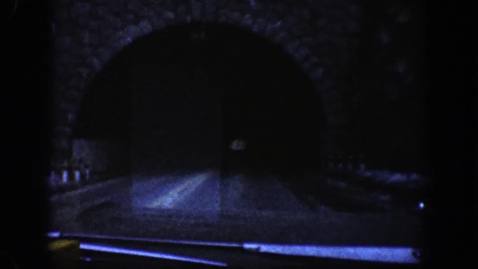 1961 Aspen-area 8mm view toward a dark stone-arch highway tunnel from a car on the road.