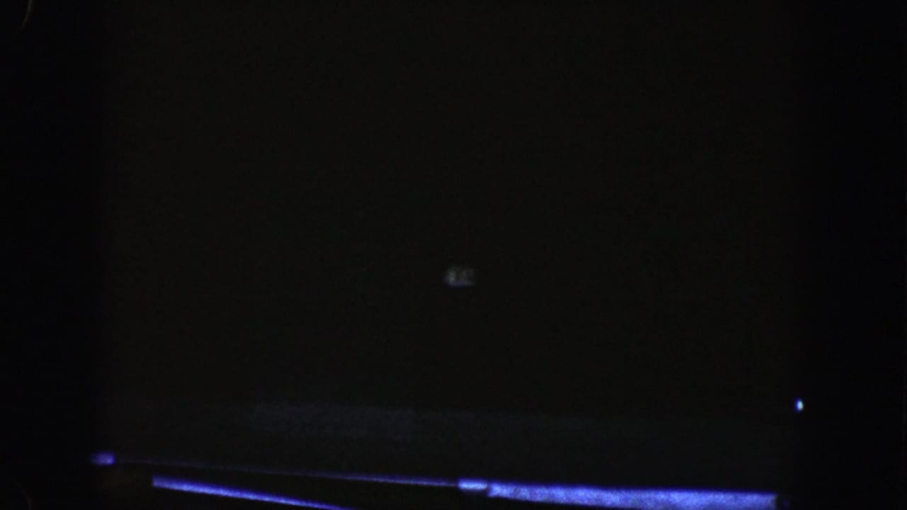 Nearly dark tunnel interior with faint blue road edge and small light marks.