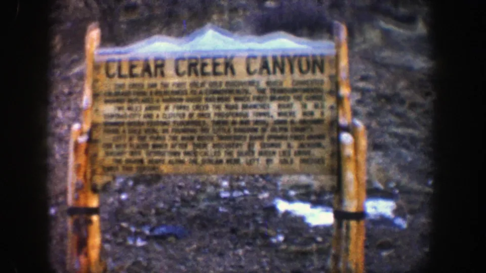 Final close view of the Clear Creek Canyon wooden historical sign, with soft focus, visible film grain, and snow patches at its base.