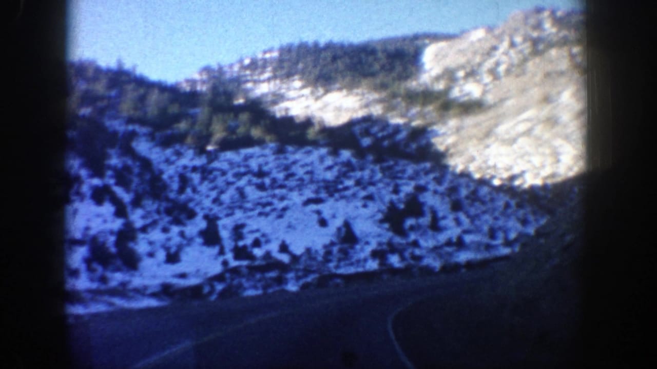 Winding road through snow-dusted hills and rocky slopes.