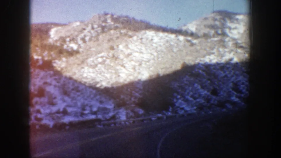 Snowy Rocky Mountain slope and roadside curve in a color 8mm Colorado travel shot from 1961.