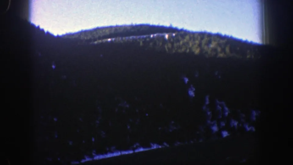Aspen, Colorado road-trip frame with a forested mountain ridge and deep 8mm vignetting from the moving-car viewpoint.