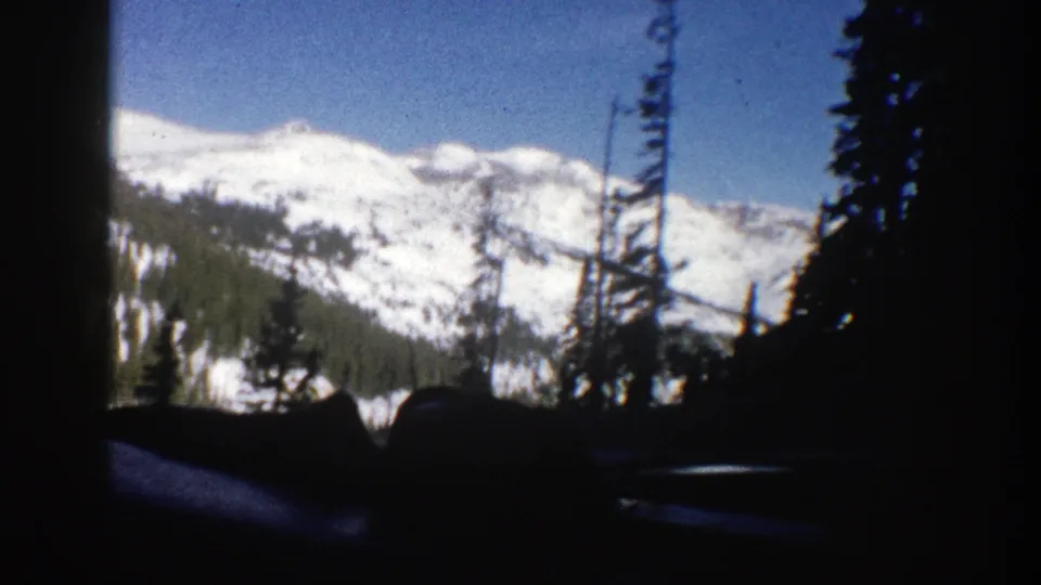 Aspen, Colorado 8mm frame showing a snow-covered ridge and conifer silhouettes through a vehicle window.