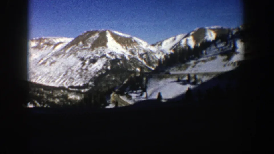1961 Aspen, Colorado home-movie view of distant snow-covered peaks and darker foreground hills in winter light.