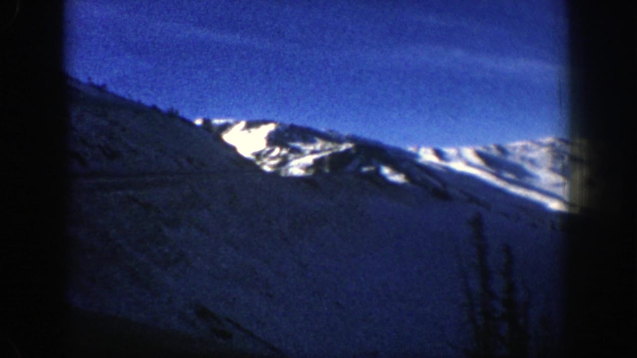 Snowy mountain ridge under a deep blue sky with dark film-frame borders.