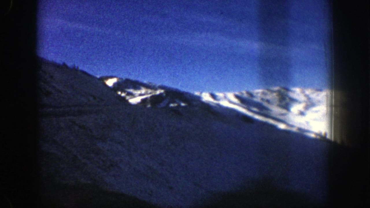 Distant snow-covered peaks and dark hillside seen through an 8mm frame.