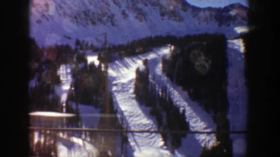 1961 Aspen winter view with ski tracks, evergreens, and a visible lift or utility structure on the snowy slope.