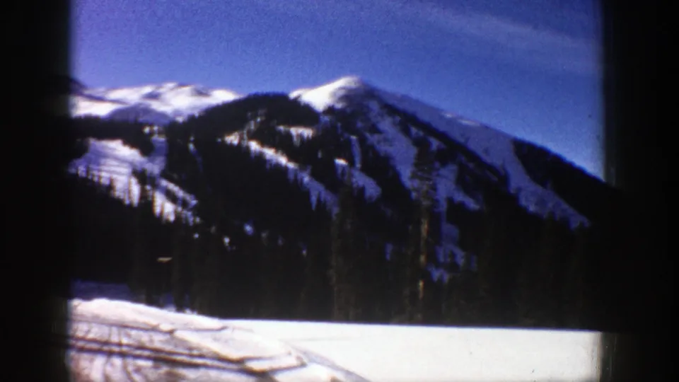 Aspen, Colorado winter scenery from 1961, showing snowy ridges, evergreen trees, and open snow beside the road.