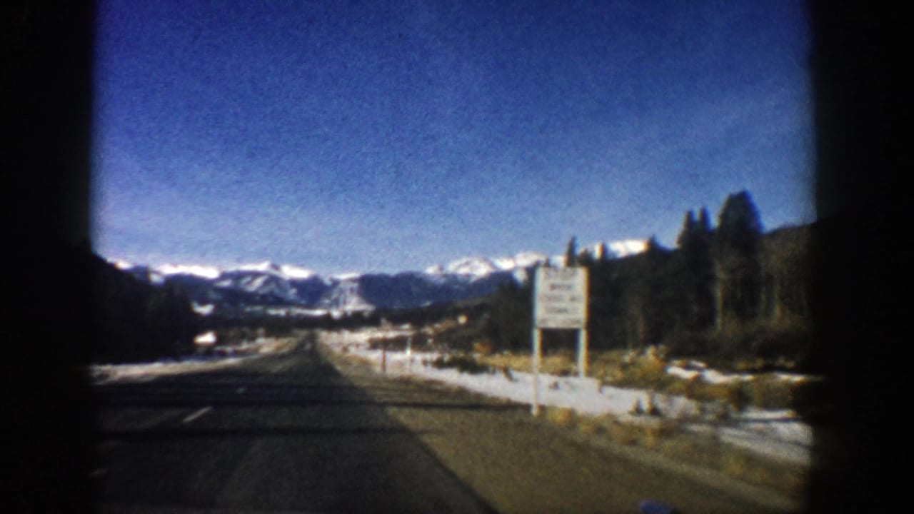 1961 Aspen, Colorado home-movie view from a moving car on a road toward snow-capped mountains.
