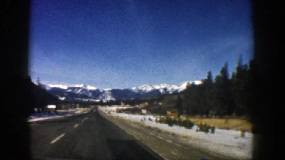 Aspen, Colorado 8mm travel frame showing a moving-road approach through snow-dusted mountain terrain.