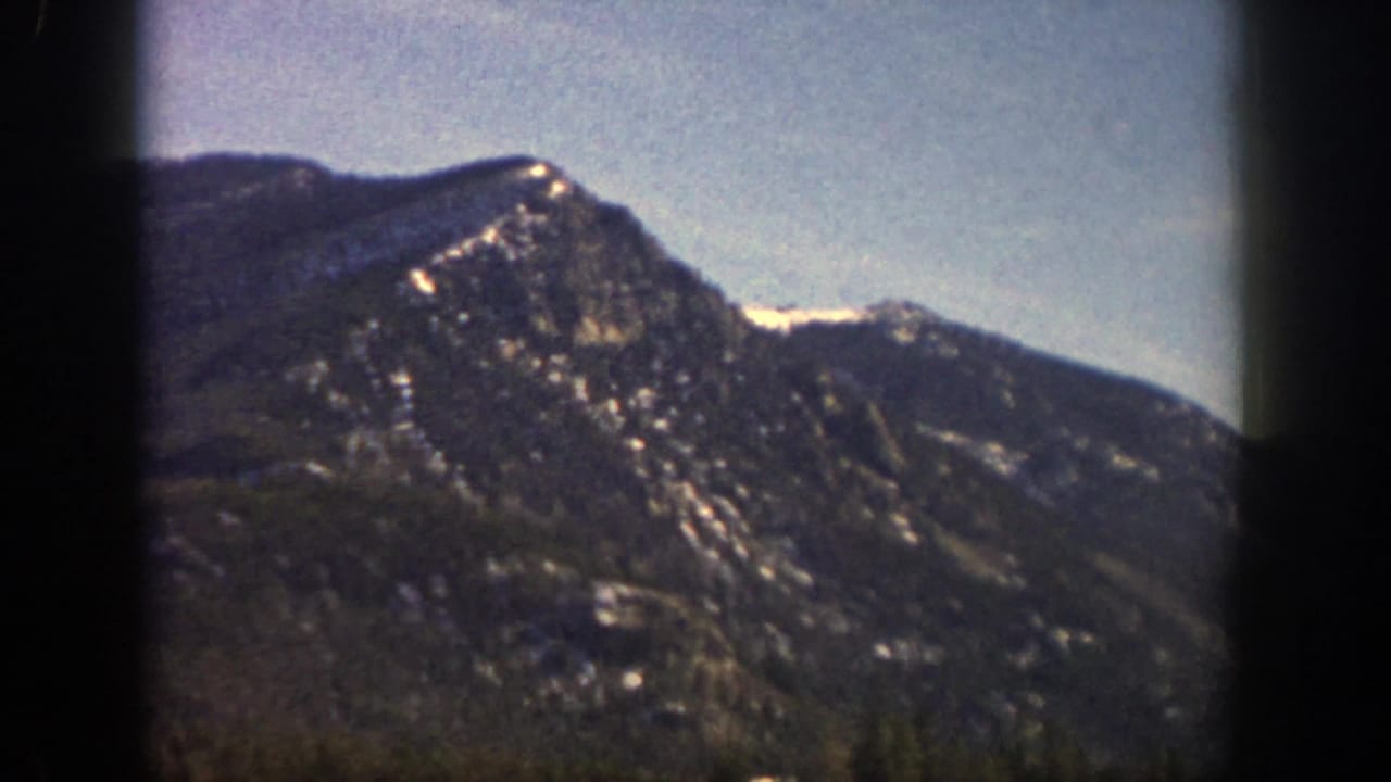 Rocky mountain ridge with scattered snow and dark vertical film border.