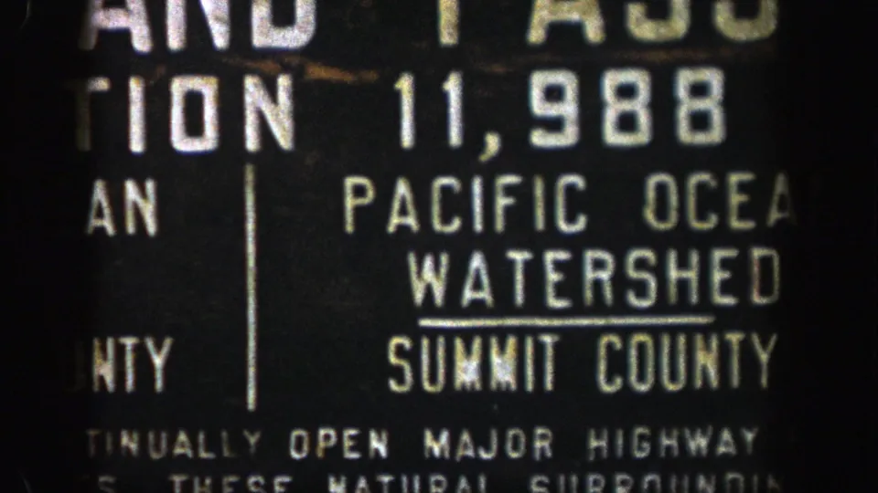 1961 Colorado 8mm frame showing part of a weathered Pacific Ocean Watershed sign in Summit County.