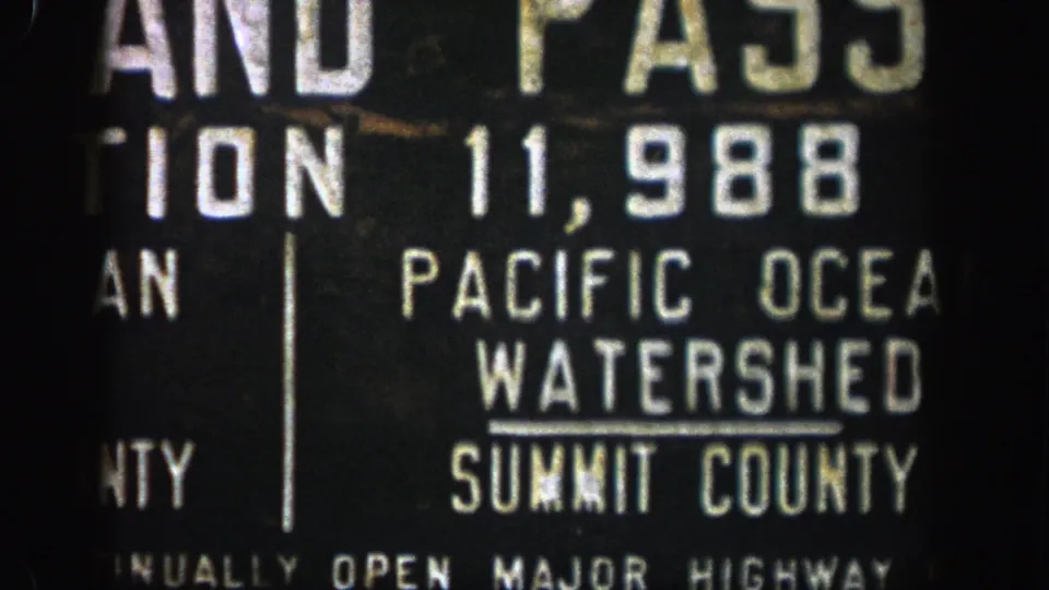 Aspen-area 8mm frame showing a soft, cropped close-up of a highway sign with watershed and county information.
