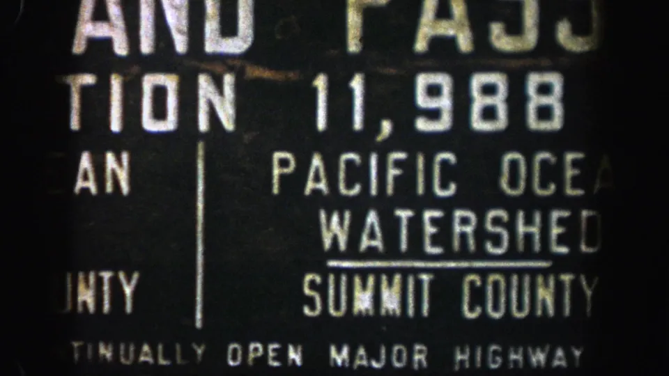 1961 8mm close-up of a Colorado roadside sign, with Pacific Ocean Watershed and Summit County lettering centered in frame.