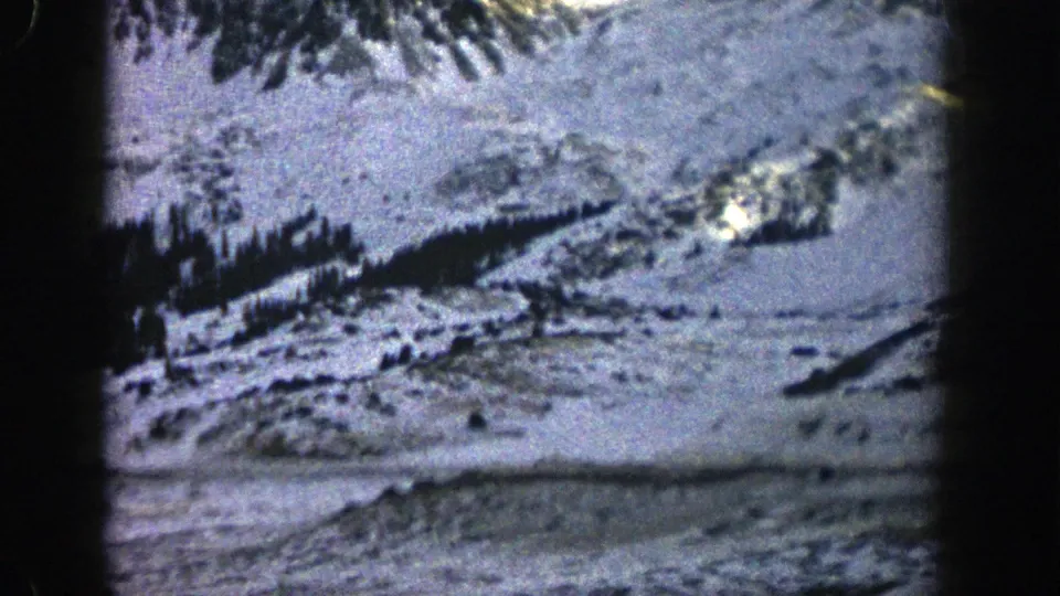 1961 Colorado mountain view showing a snowy hillside, scattered trees, and soft 8mm color exposure.