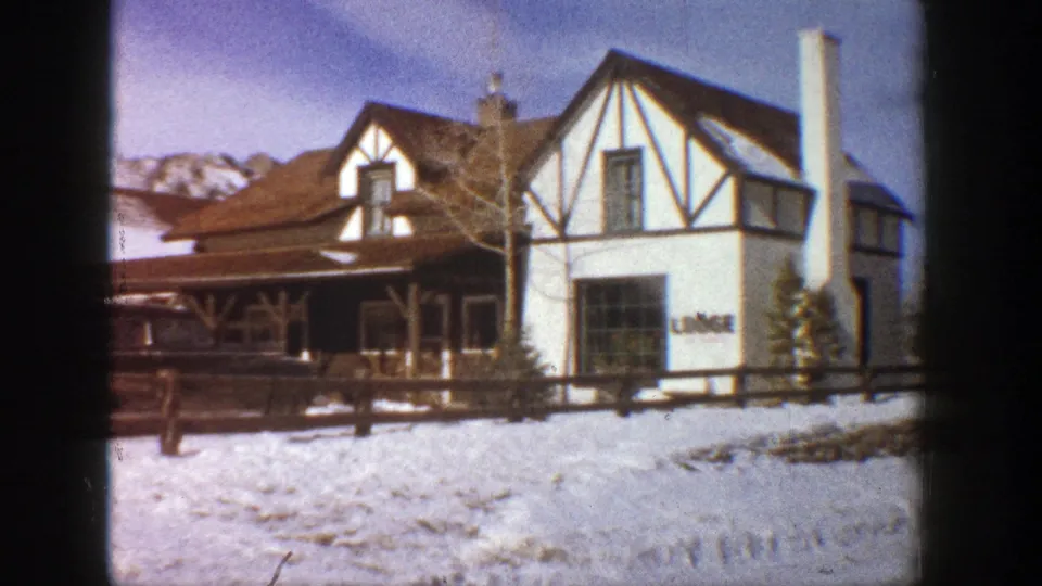 Snowy Aspen lodge exterior in 1961, showing timber-frame architecture, a wooden fence, and visible lodge signage.