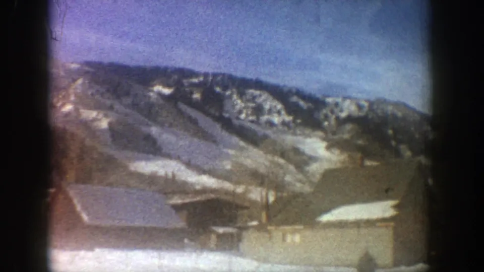 1961 Aspen view with rooftops in the foreground and snow-streaked mountain slopes across the background.