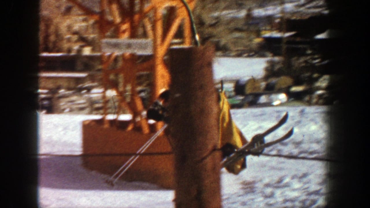 Skis and poles near a wooden ski lift structure on snowy ground.