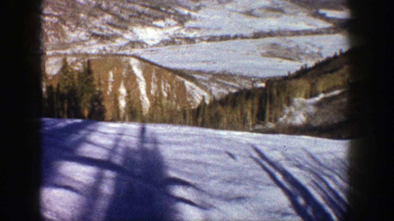 Snowy mountain slope seen through dark vertical frame edges.